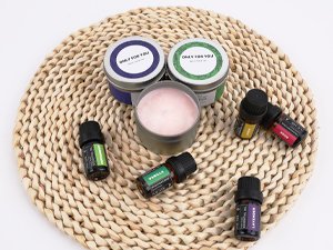 Soy candle making kit contents including essential oil bottles, wax blocks, and tins on a woven mat.