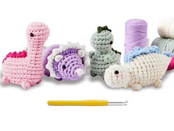 Crocheted dinosaur and turtle figures with yarn and crochet hook on white background