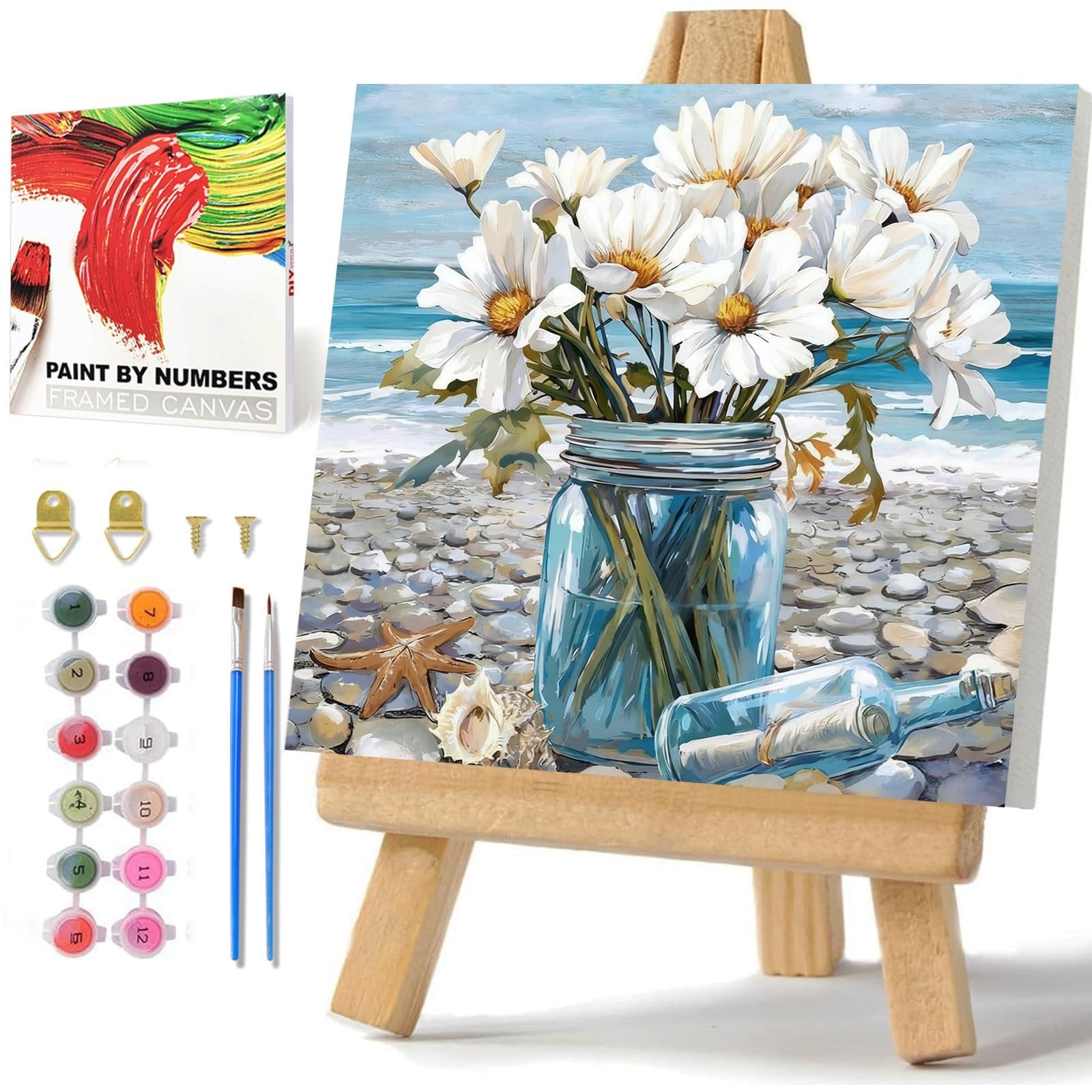 Paint by numbers kit with framed canvas, paints, brushes, and hardware on a wooden easel, featuring a floral beach scene.
