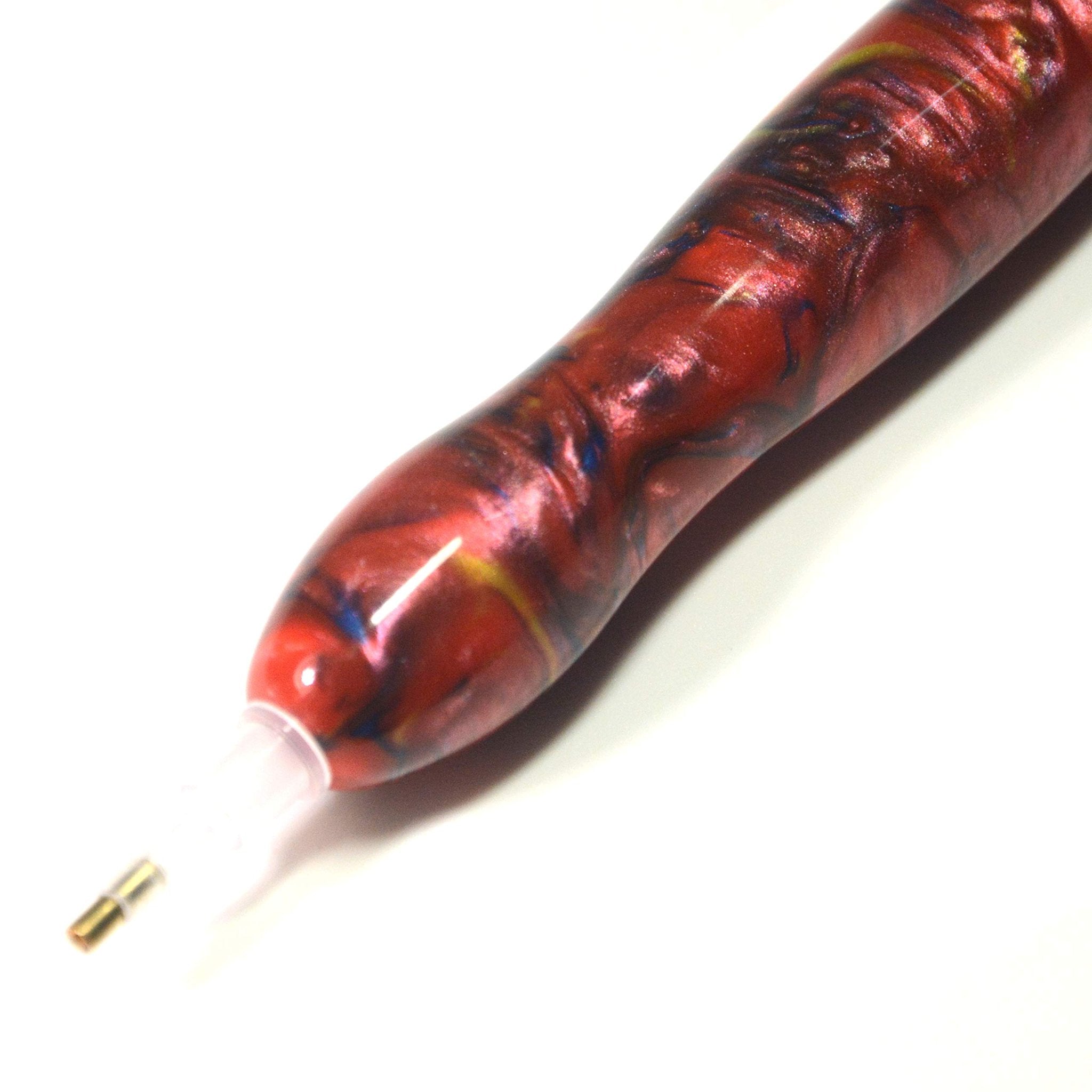 Close-up of a red and blue marbled diamond painting drill pen with a gold tip on a white background.