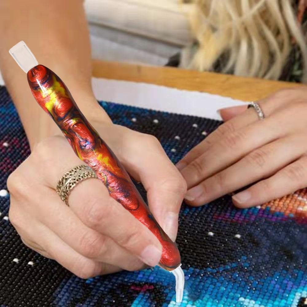 Diamond painting drill pen with artistic red and yellow swirl pattern being used on a canvas