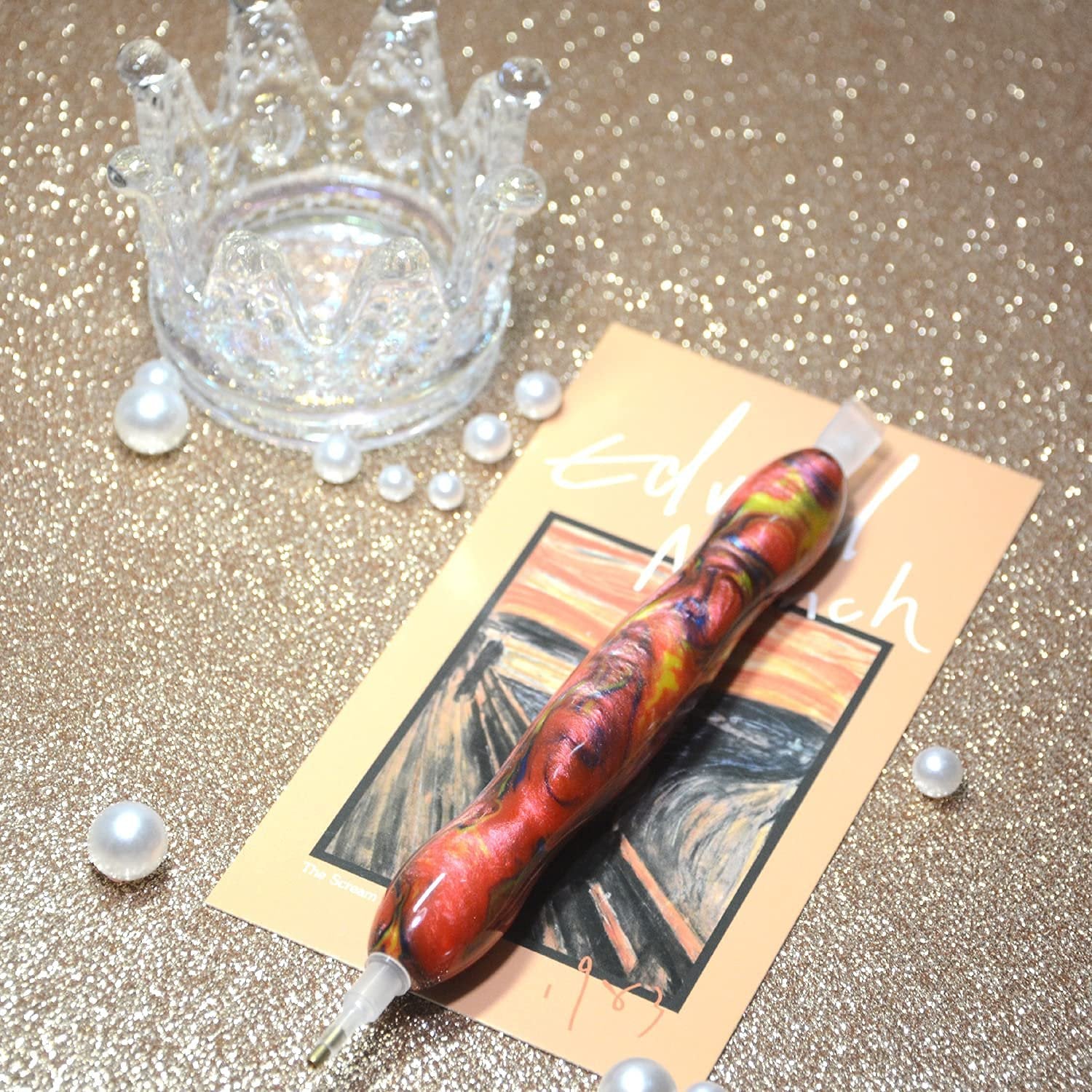 Diamond painting drill pen with red and yellow swirls on a card featuring 'The Scream' painting, surrounded by pearls and a crown.