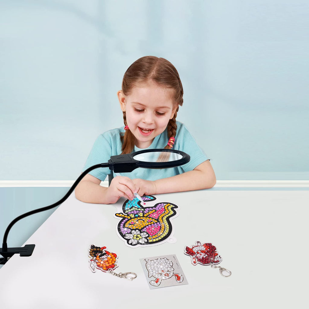 Young girl using a magnifying lamp to work on a diamond painting keychain kit