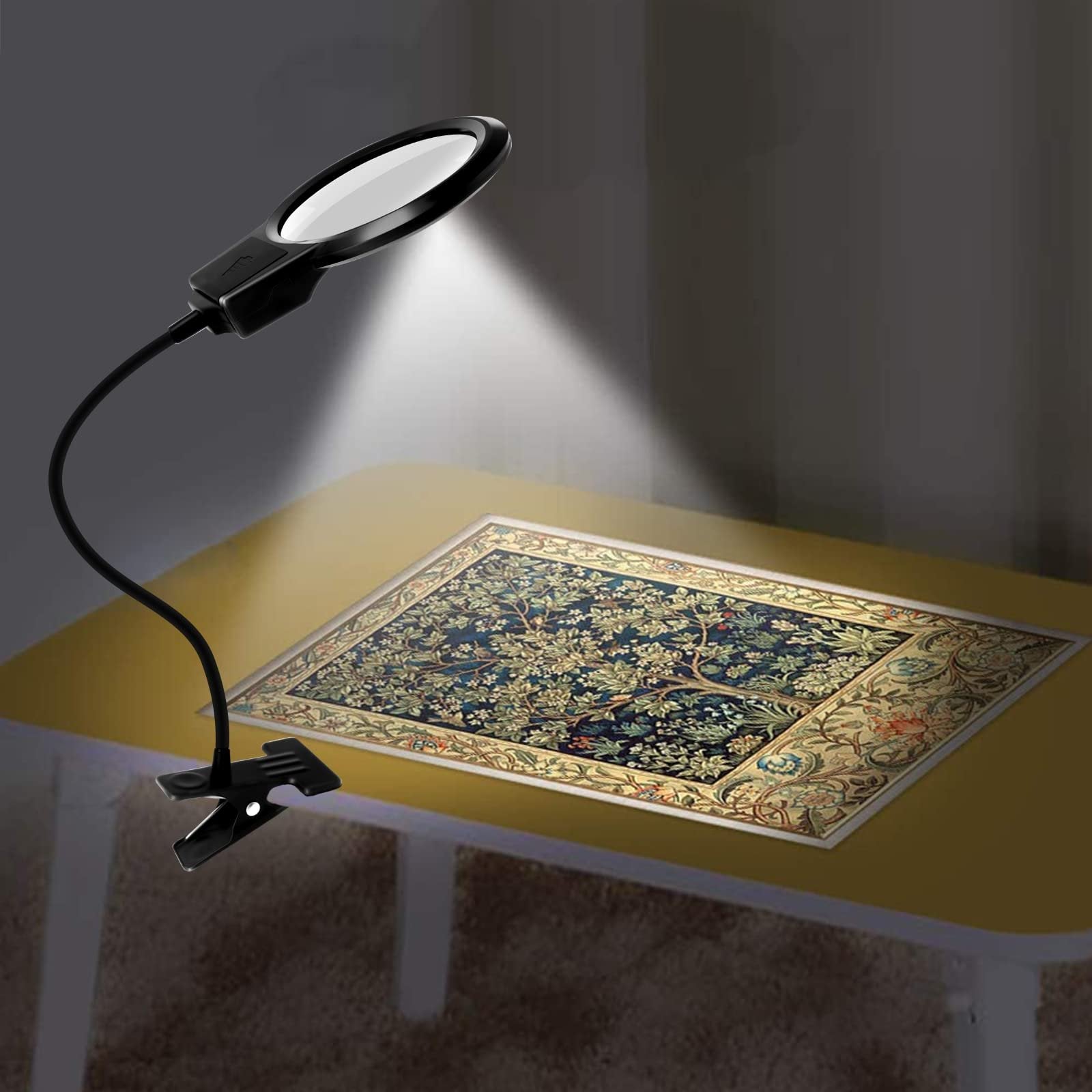 Black LED magnifier lamp with flexible gooseneck and clip attached to a table, illuminating a diamond painting.