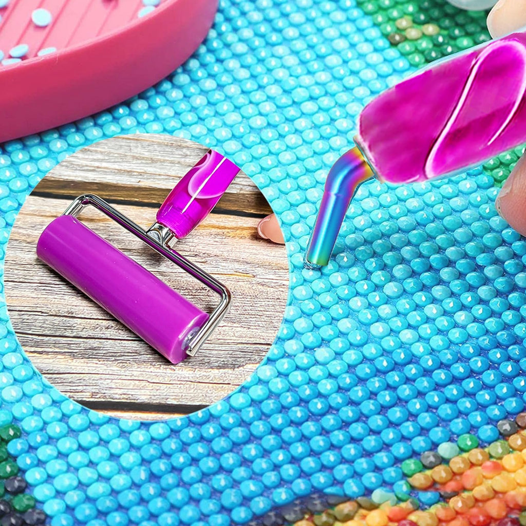 Diamond painting kit showing a purple roller tool and a diamond painting pen with a rainbow tip pressing a blue diamond onto a canvas.