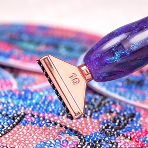 Diamond painting pen with rose gold tip on a colorful beaded canvas, close-up shot
