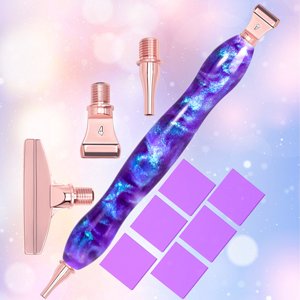 Diamond painting pen kit with purple and blue galaxy resin pen, rose gold tips, and purple wax squares against a soft bokeh background.