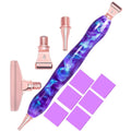Diamond painting pen kit with purple and blue galaxy resin pen, rose gold tips, and purple wax squares on a white background.