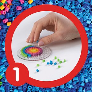 Hand placing colorful fuse beads onto a pegboard to create a circular design, surrounded by loose beads.