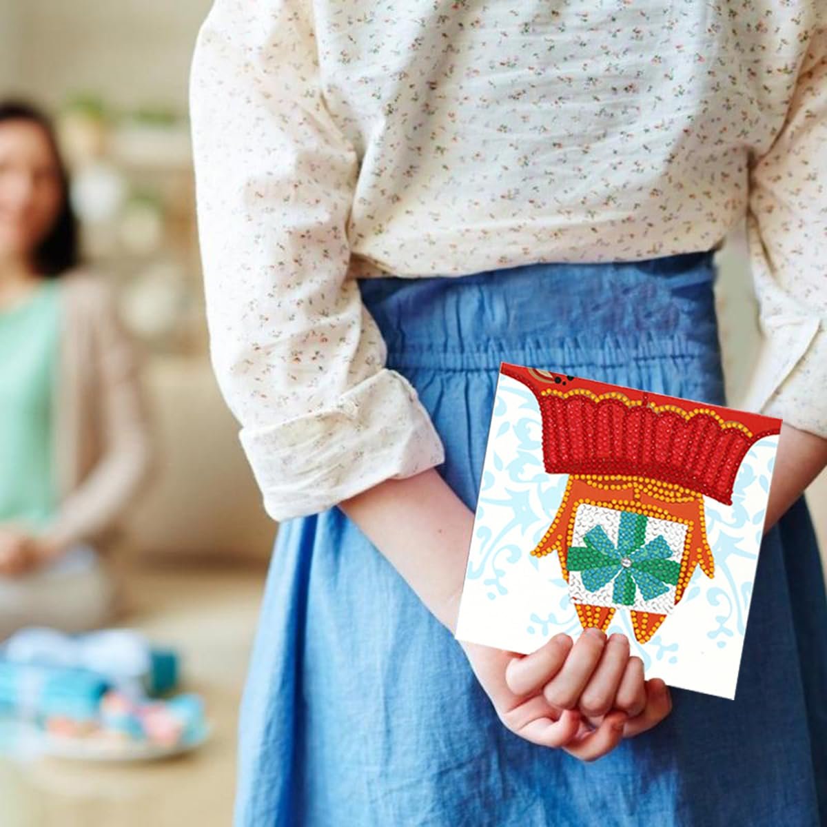 Child holding a diamond painting Christmas card featuring an orange owl with a gift, behind their back.