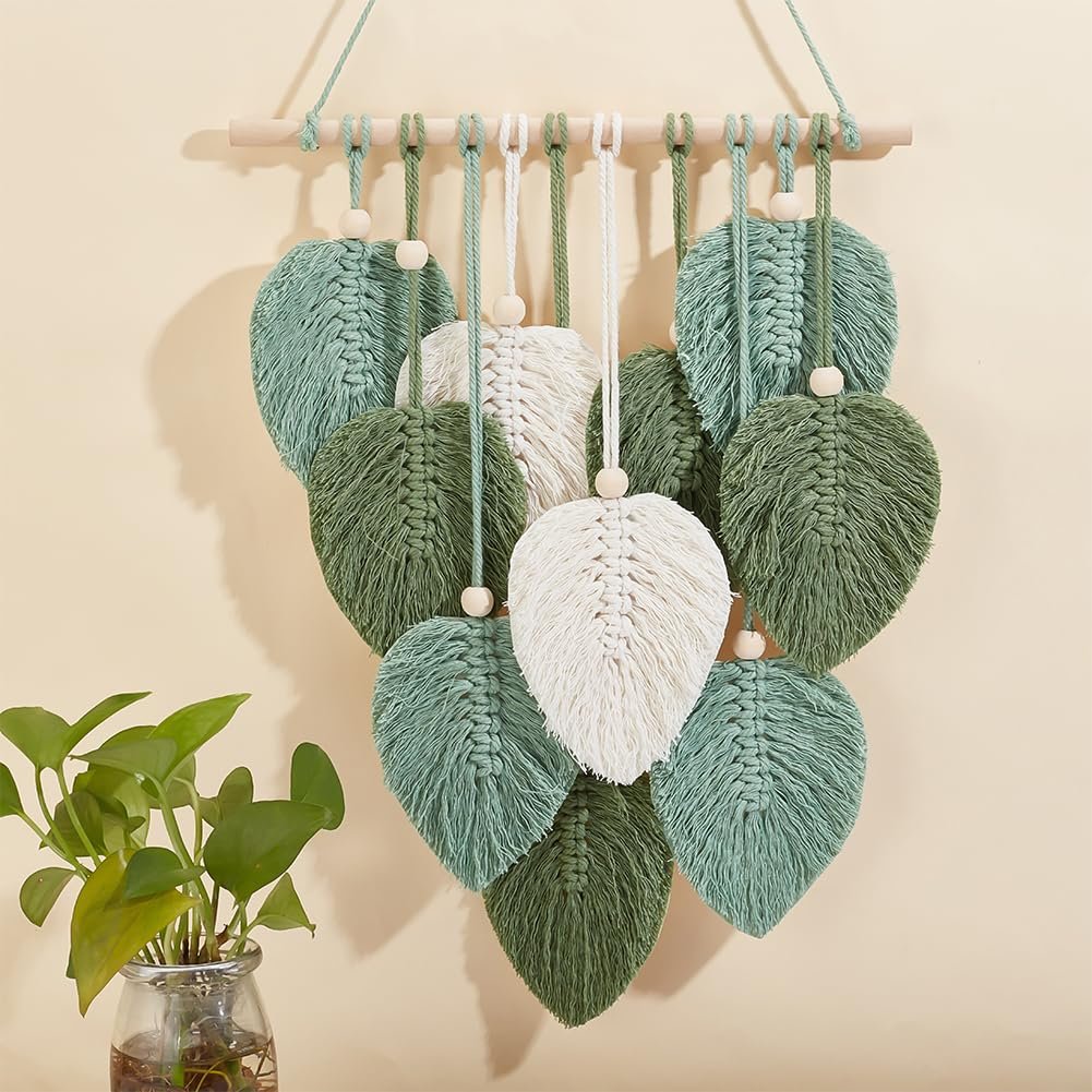 Macrame leaf wall hanging with wooden beads and a wooden dowel, displayed with a potted plant.