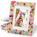 DIY mosaic picture frame craft kit with assorted colorful embellishments and tools, featuring a photo of four smiling girls.