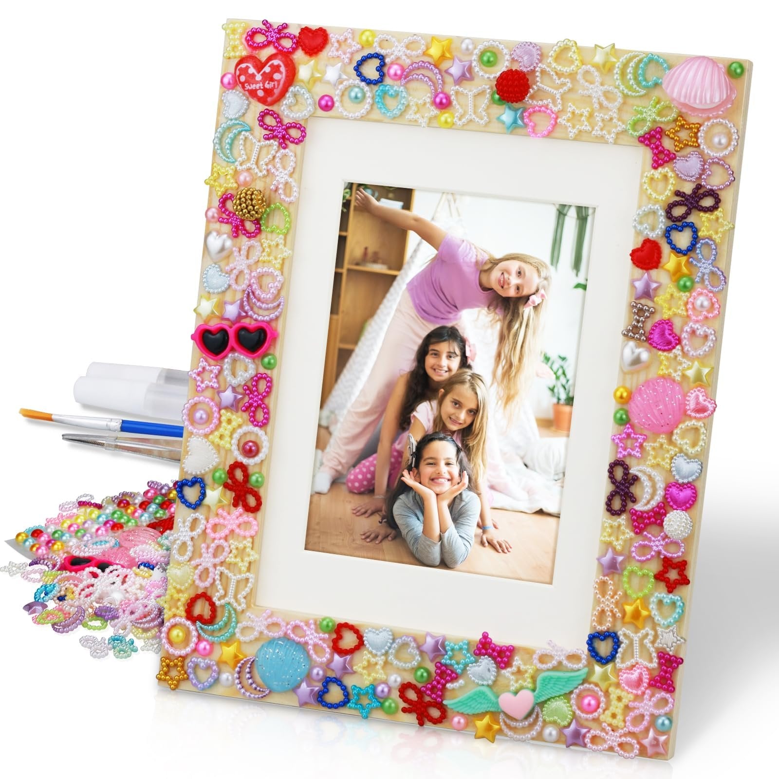 DIY mosaic picture frame craft kit with assorted colorful embellishments and tools, featuring a photo of four smiling girls.