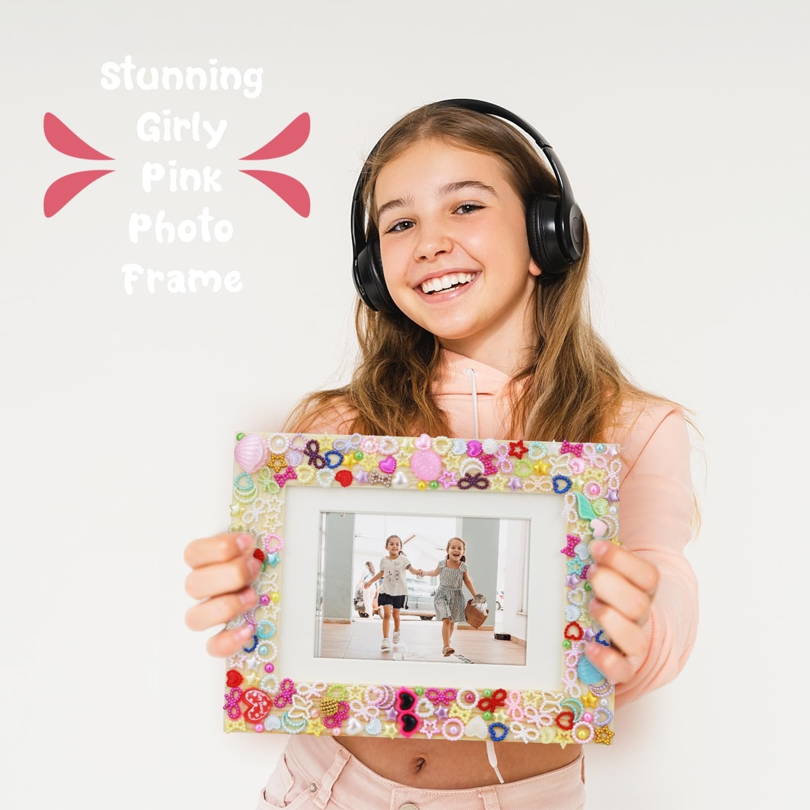 Smiling girl wearing headphones holds a decorated DIY mosaic picture frame with a photo of two girls inside.