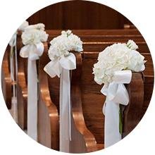 White satin ribbon and flowers decorating church pews for a wedding ceremony