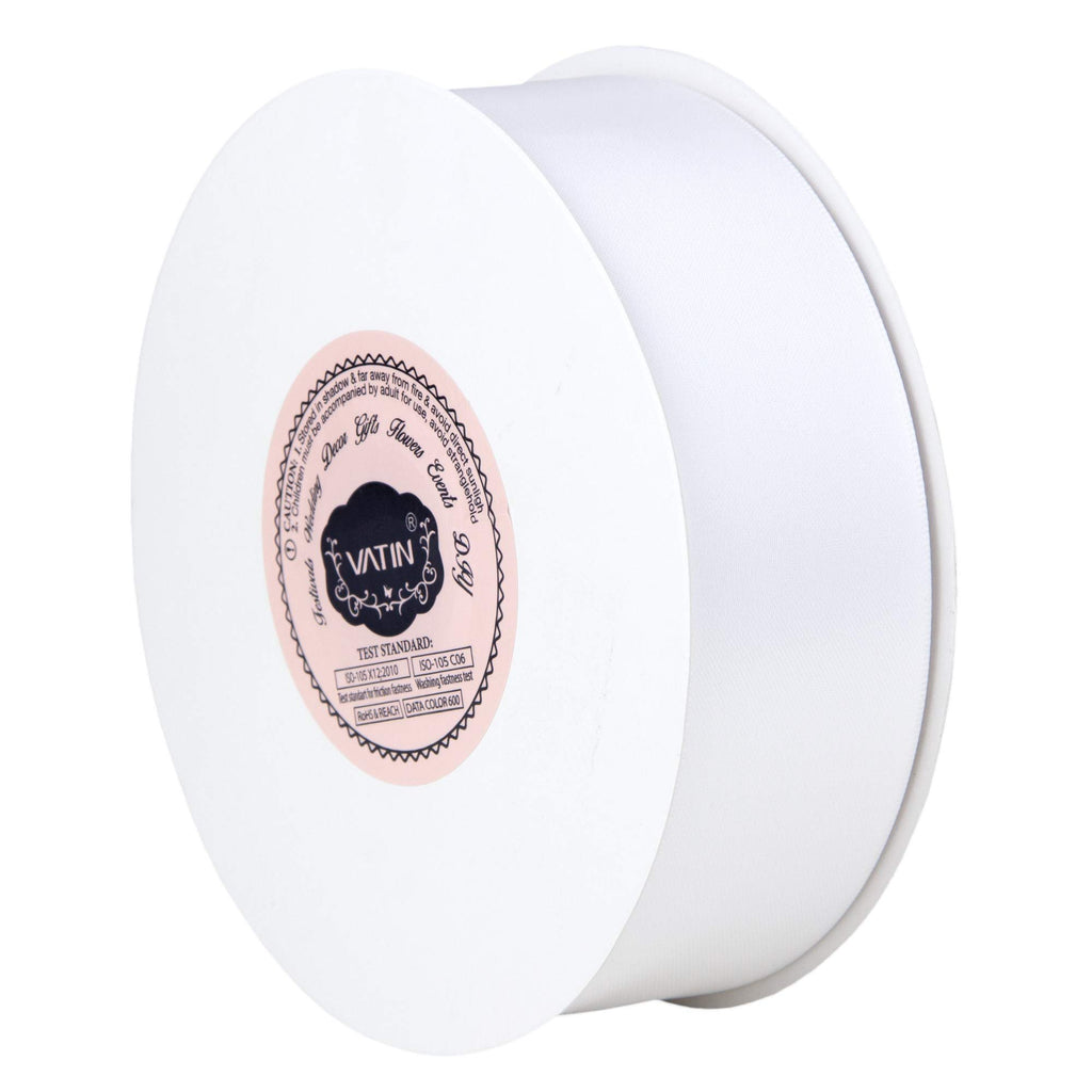 Spool of white double-face satin ribbon with a pink and black label showing product information and brand name.
