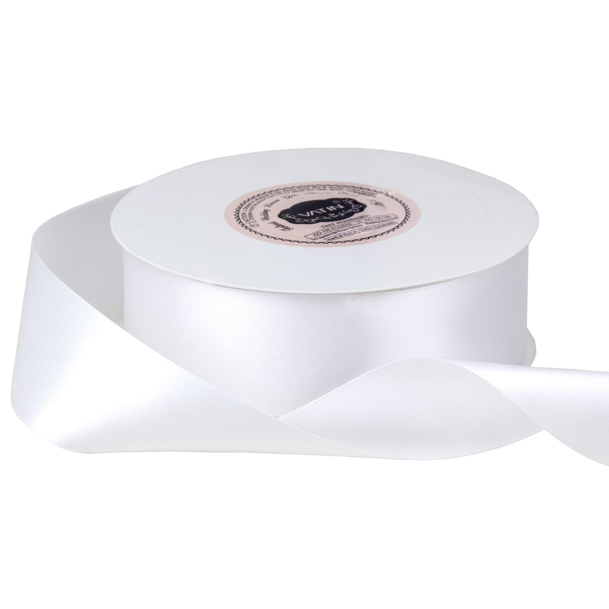 White satin ribbon on a spool, with a label on the spool showing product information.