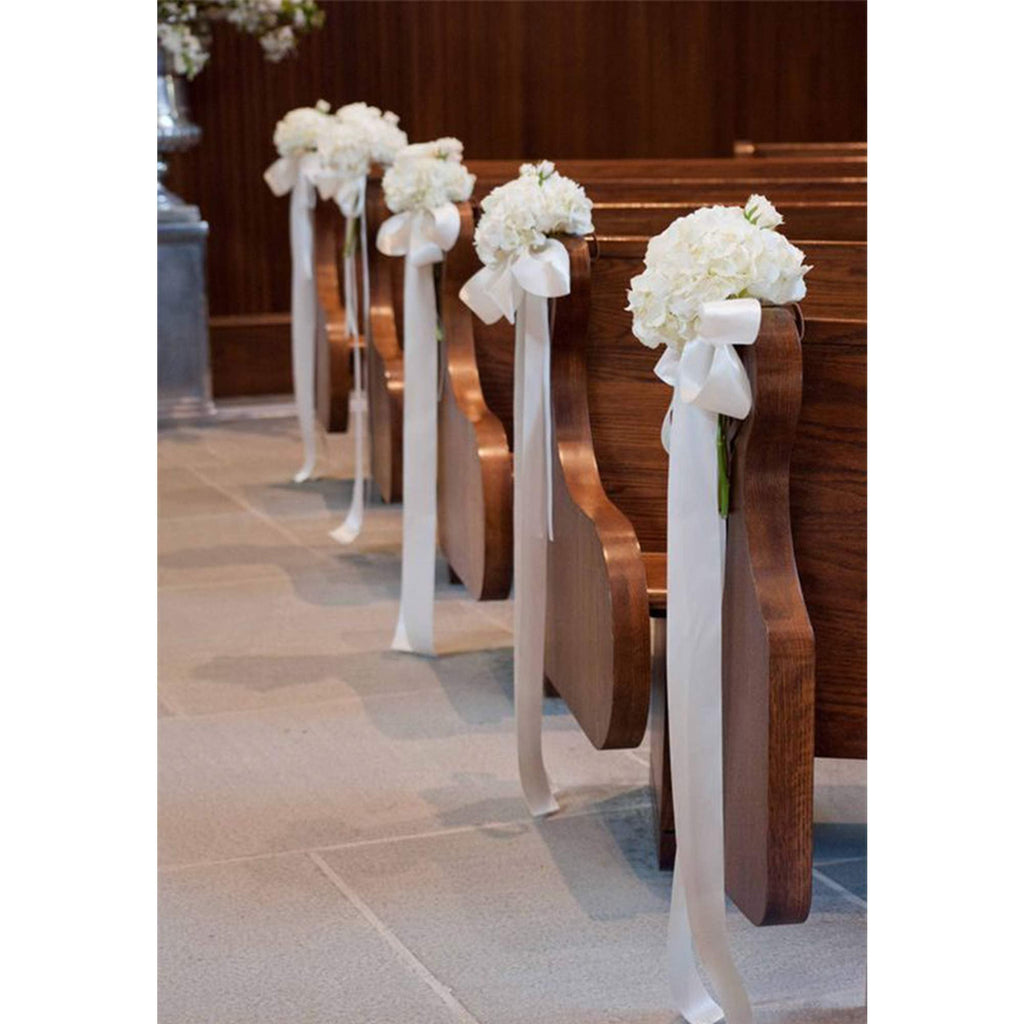 White satin ribbon tied with white flowers to decorate church pews for a wedding ceremony.