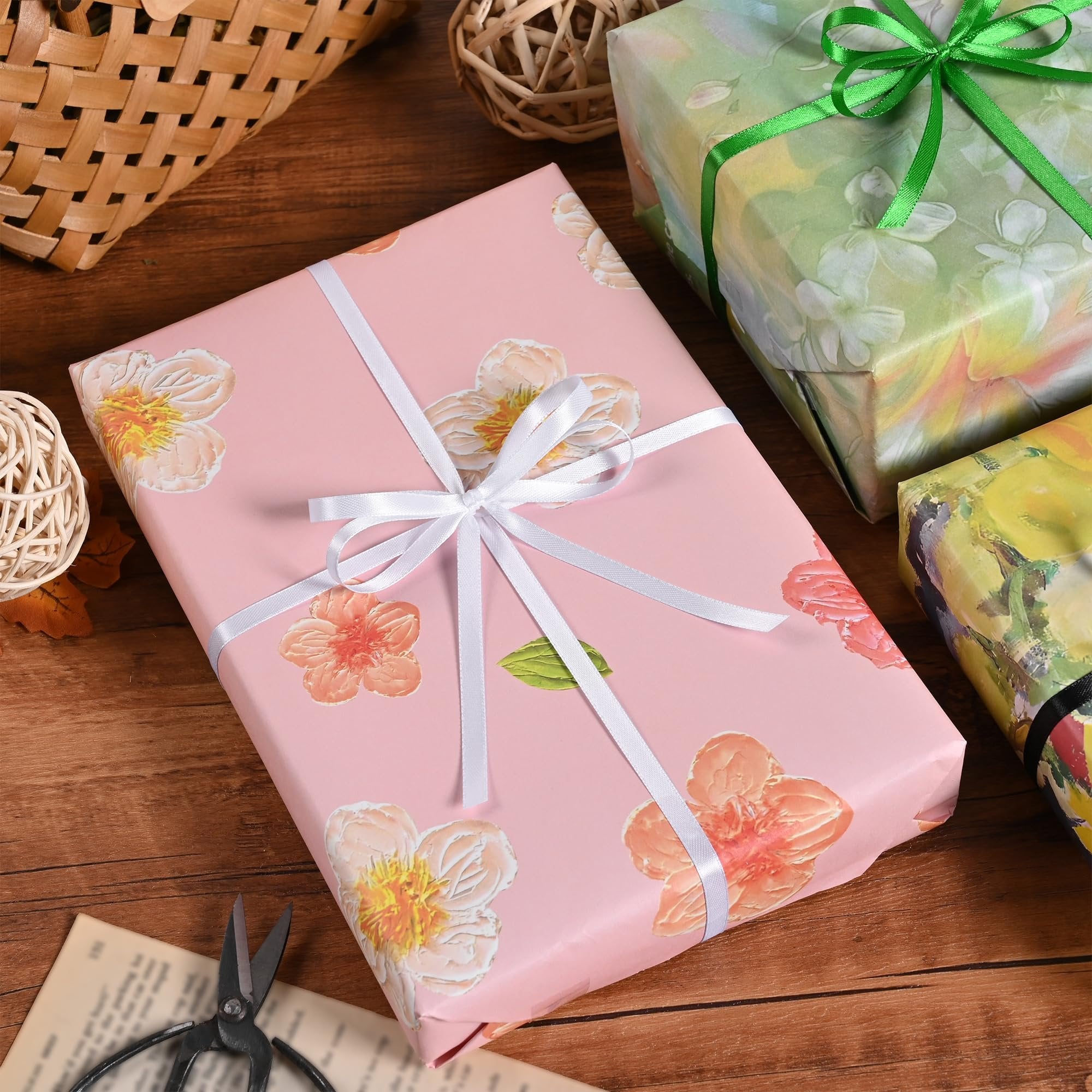 Wrapped gifts with floral patterns and ribbons on a wooden surface with decorative baskets and scissors