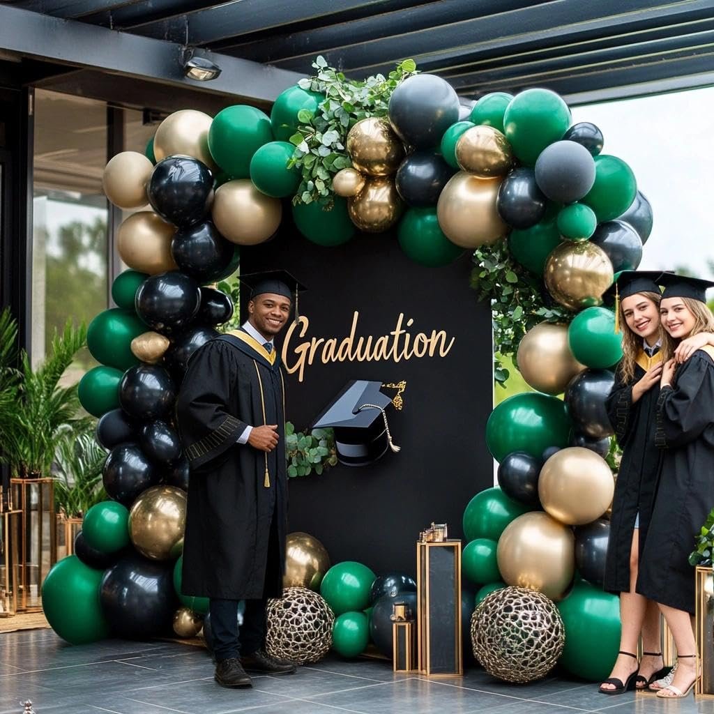 Graduation party scene with a balloon arch in dark green, black, and metallic gold, featuring two graduates posing.