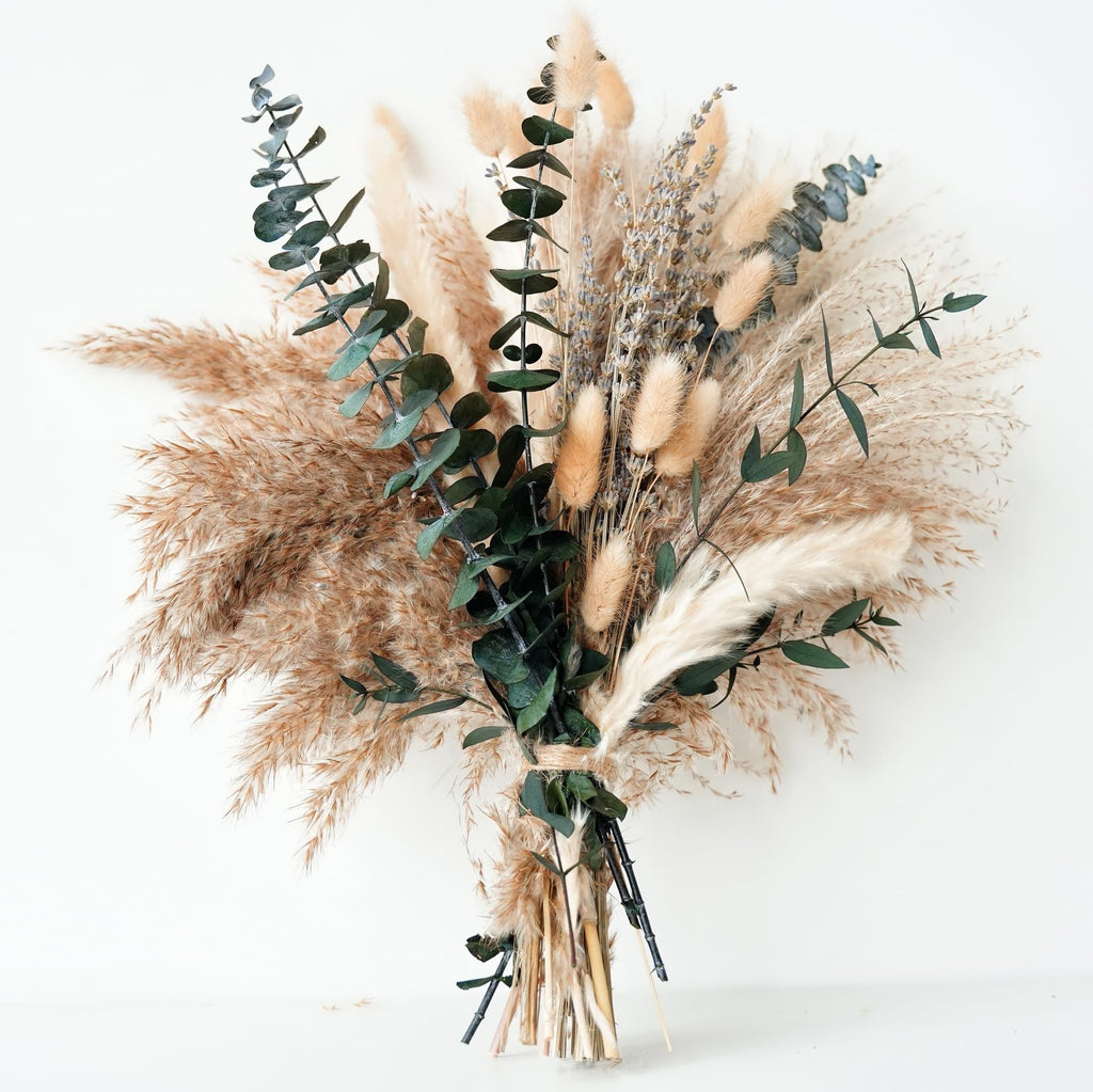 Dried boho flower bouquet with pampas grass, lavender, eucalyptus, and rabbit tail tied with twine, against a white background.