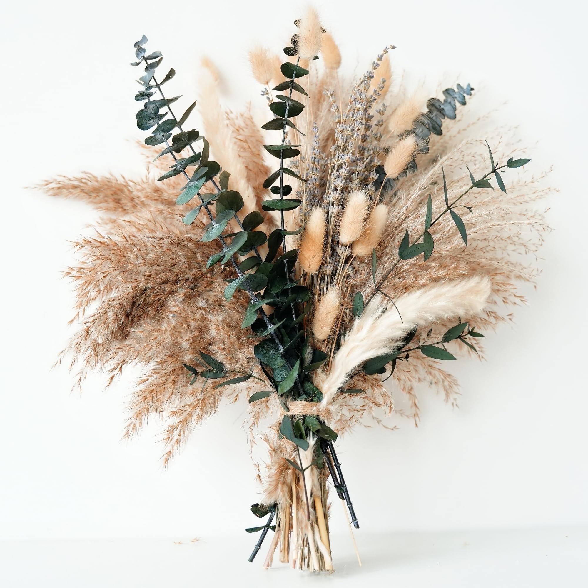 Dried boho flower bouquet with pampas grass, lavender, eucalyptus, and rabbit tail tied with twine, against a white background.