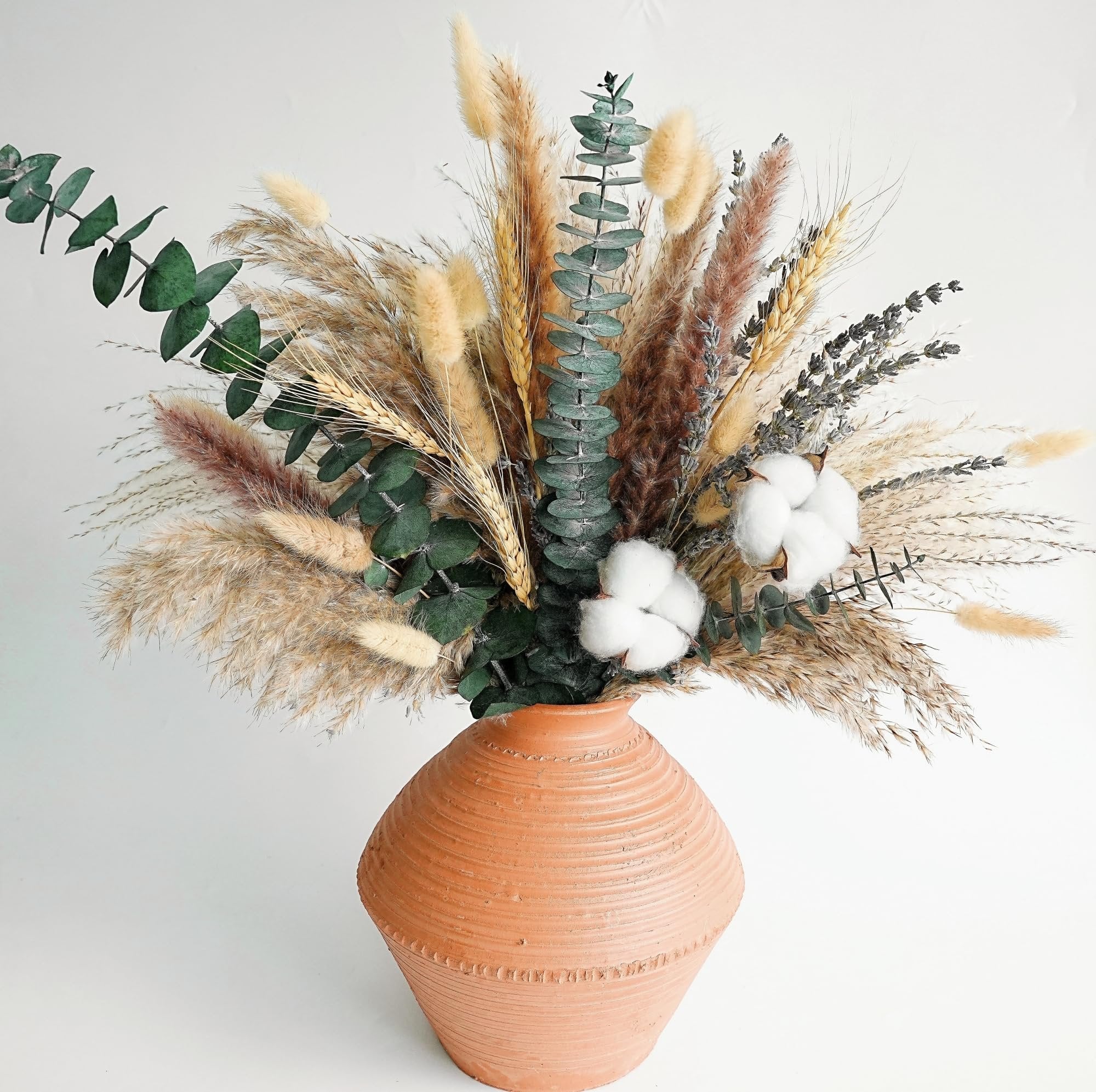 Dried flower bouquet with pampas grass, eucalyptus, cotton, and lavender in a terracotta vase.
