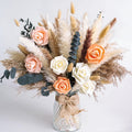 Dried flower bouquet with pampas grass and faux roses in a textured glass vase tied with burlap ribbon.