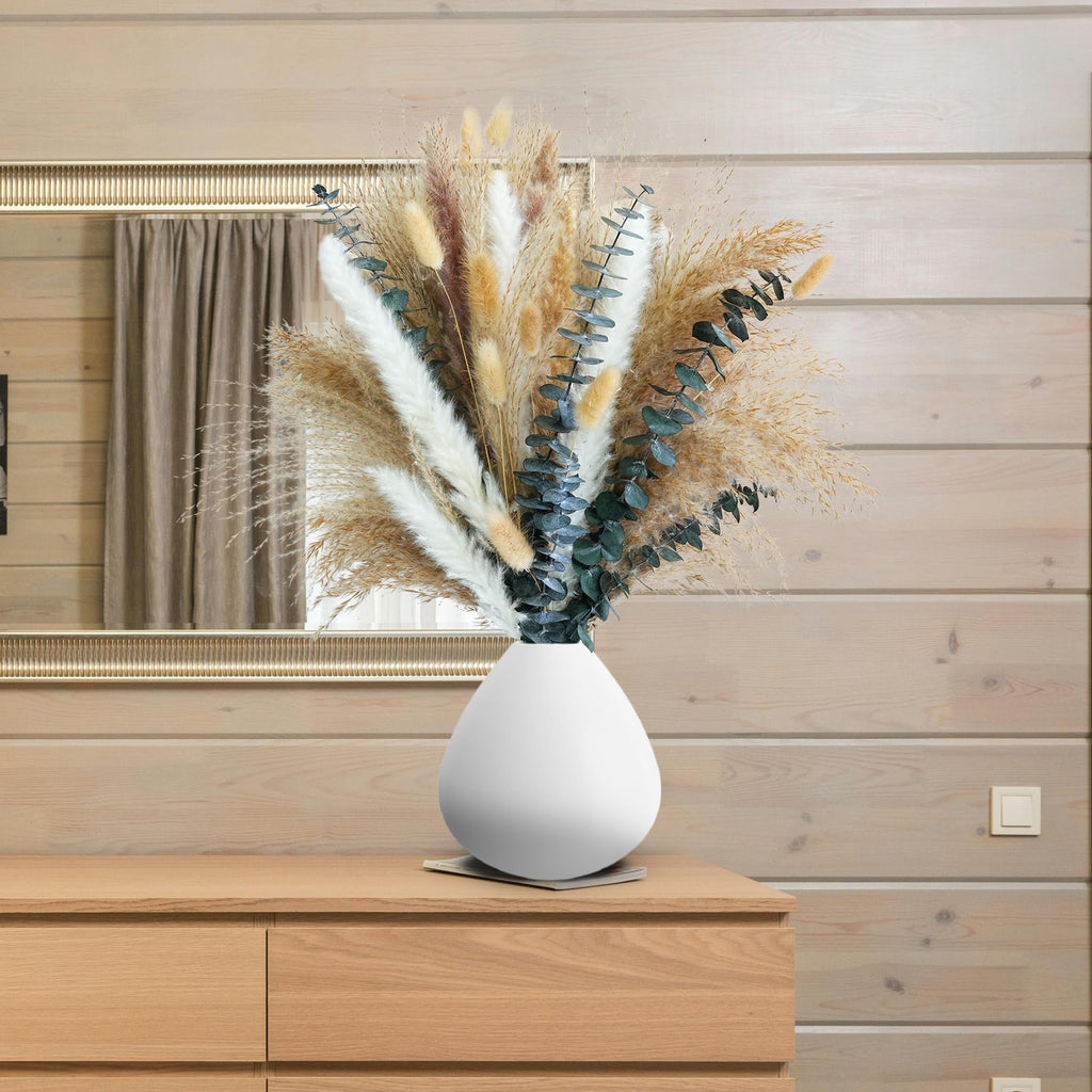 Boho dried pampas grass and eucalyptus bouquet in a white vase on a wooden dresser, reflected in a mirror.
