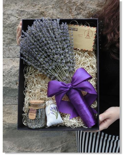 Gift box with dried lavender bouquet, small jar, and sachet, held by a person.
