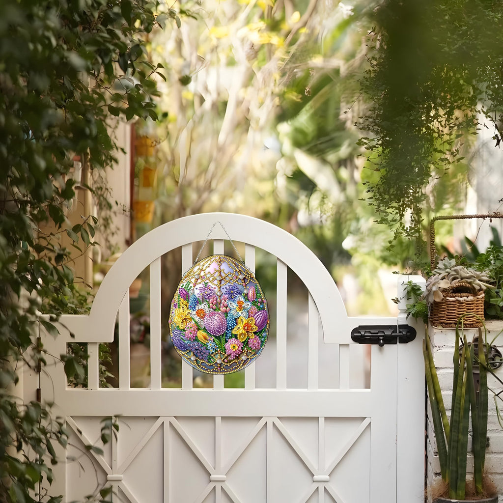 Easter egg diamond art hanging kit with floral design, displayed on a white gate outdoors.