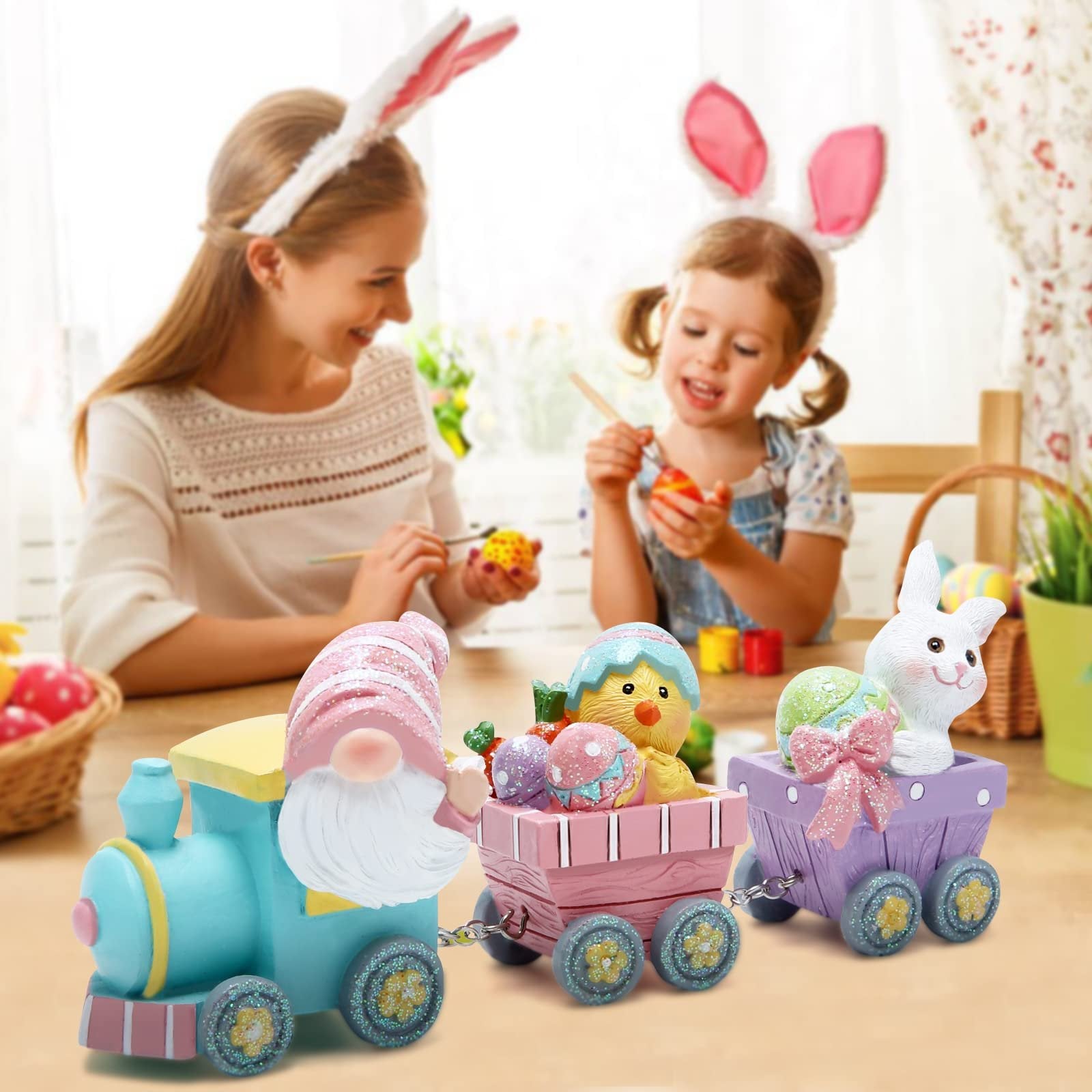 Easter train figurine with gnome, chick, and bunny carrying decorated eggs and carrots, with a mother and child painting in the background.