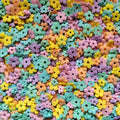 Assorted pastel edible flower-shaped sprinkles scattered across a surface, close-up view.
