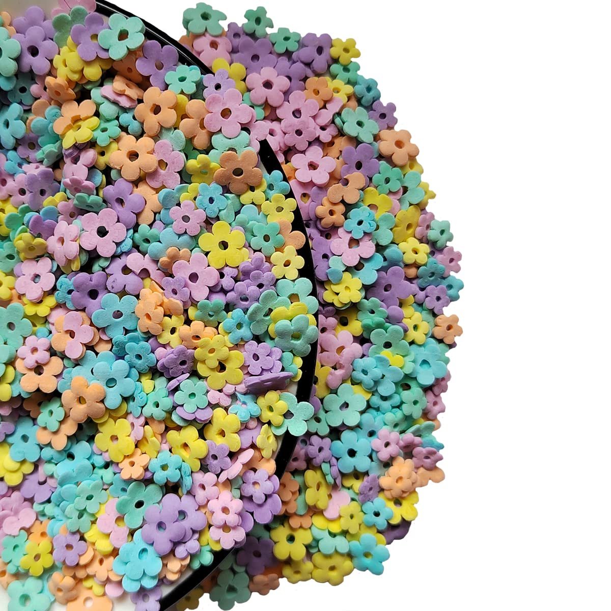 Edible pastel flower sprinkles piled in a black dish against a white background.
