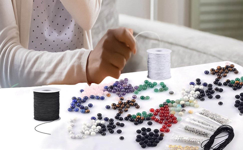 Person's hands working with colorful beads and two spools of elastic string for jewelry making.
