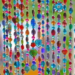 Colorful beaded strands hanging as a curtain, featuring various shapes and sizes of beads.