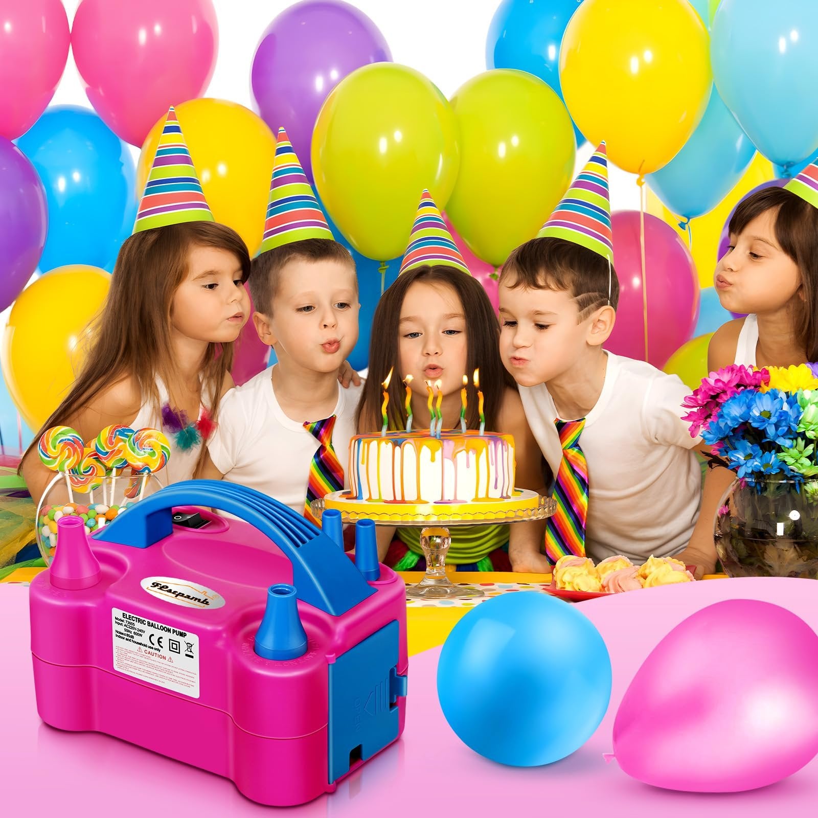 Children blowing out candles on a birthday cake with a pink electric balloon pump in the foreground.