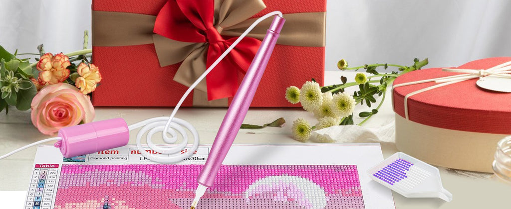 Pink electric diamond painting pen with USB cord and storage unit, shown with a diamond painting canvas, tray of beads, and gift boxes.