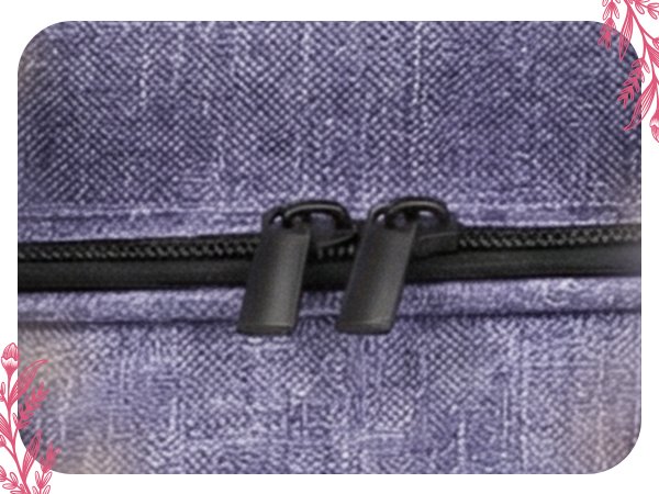 Close-up of two black zipper pulls on a textured purple storage bag.