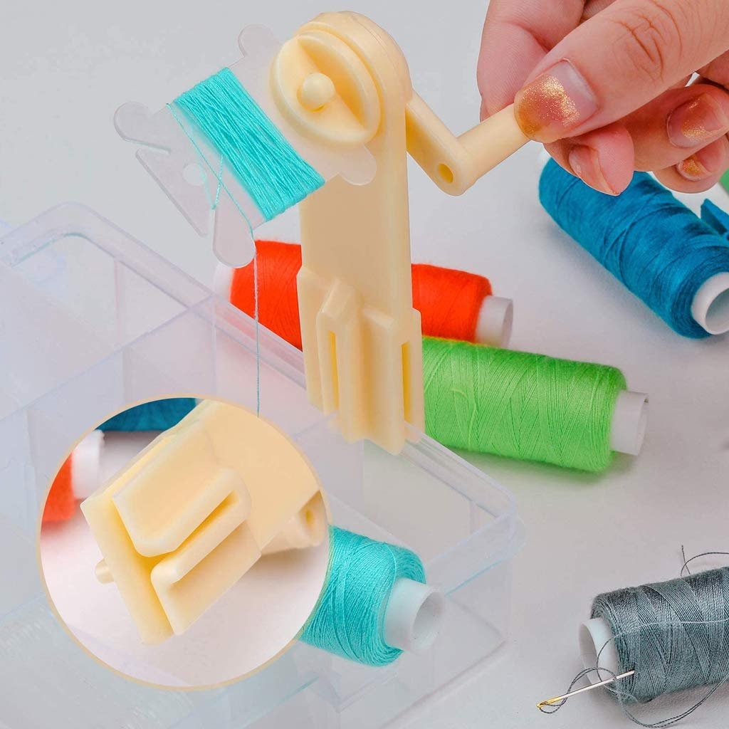 Embroidery floss organizer with a hand using a winder to wrap teal thread onto a plastic bobbin, with spools of orange, green, and blue thread in a clear storage box.