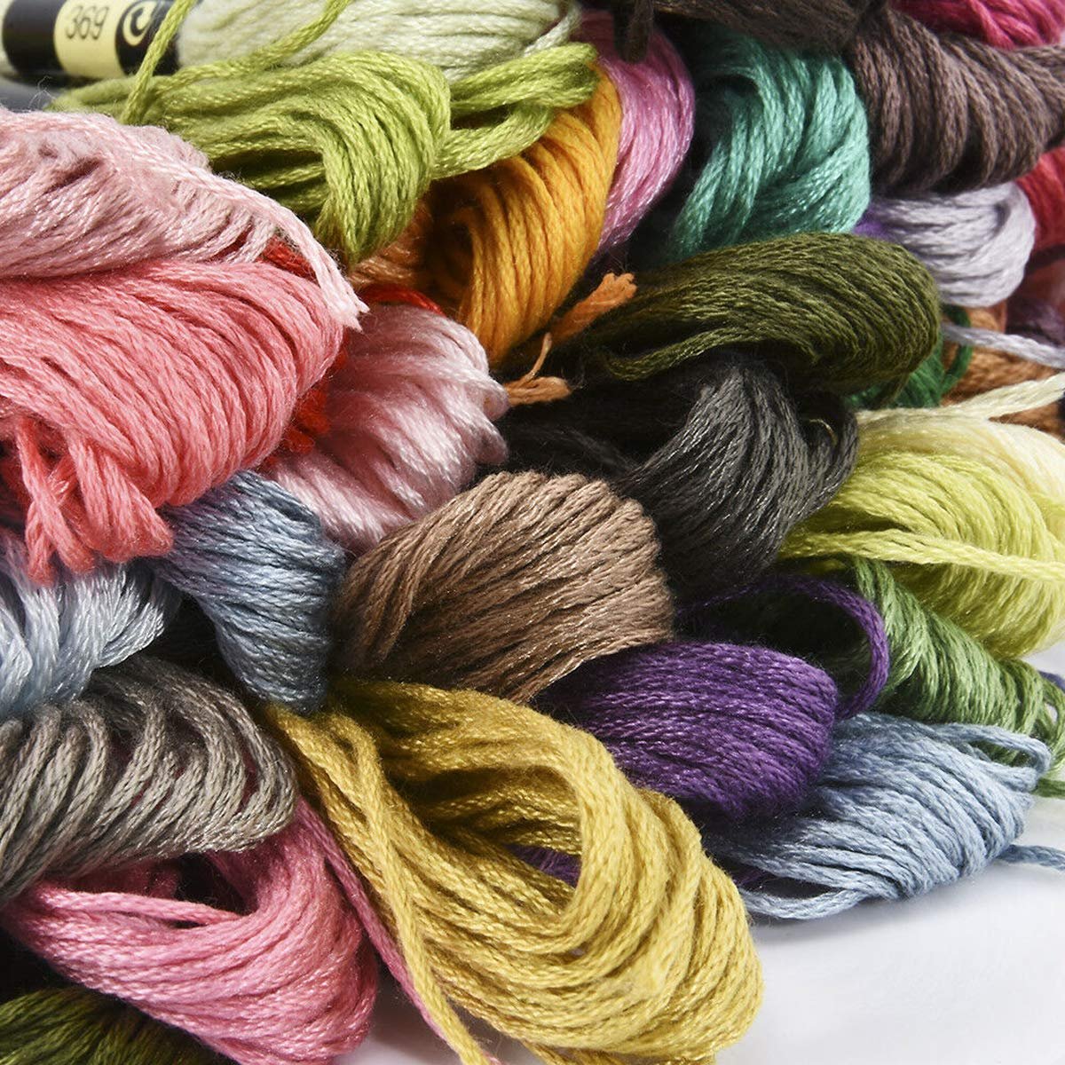 Close-up of a pile of colorful embroidery floss skeins in various shades of pink, green, yellow, purple, and blue.