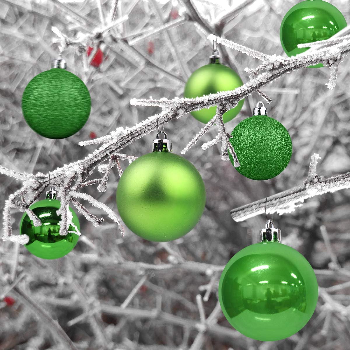 Emerald green Christmas ball ornaments with various finishes hanging on a frosted tree branch