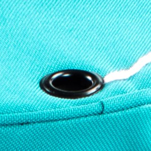 Close-up of a teal fabric yarn organizer with a grommet and white yarn passing through it.
