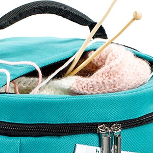 Teal crochet tote bag with knitting needles and pink yarn peeking out of an open zipper pocket.