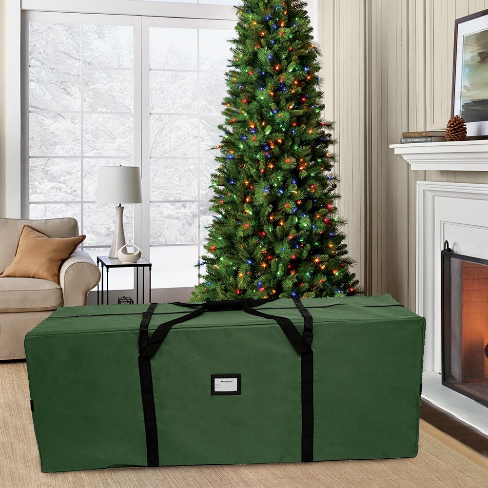 Green Christmas tree storage bag in a living room with a decorated tree behind it.