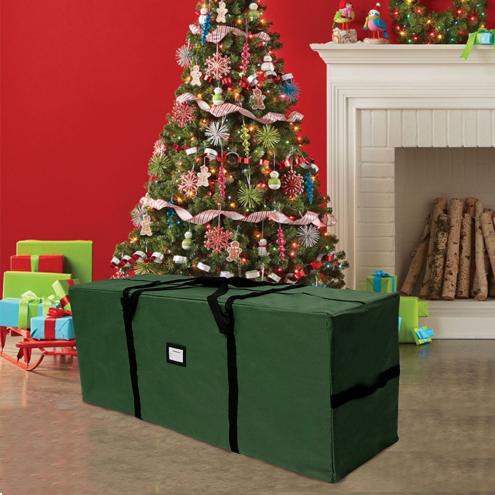 Green Christmas tree storage bag in a festive living room setting with a decorated tree and fireplace.