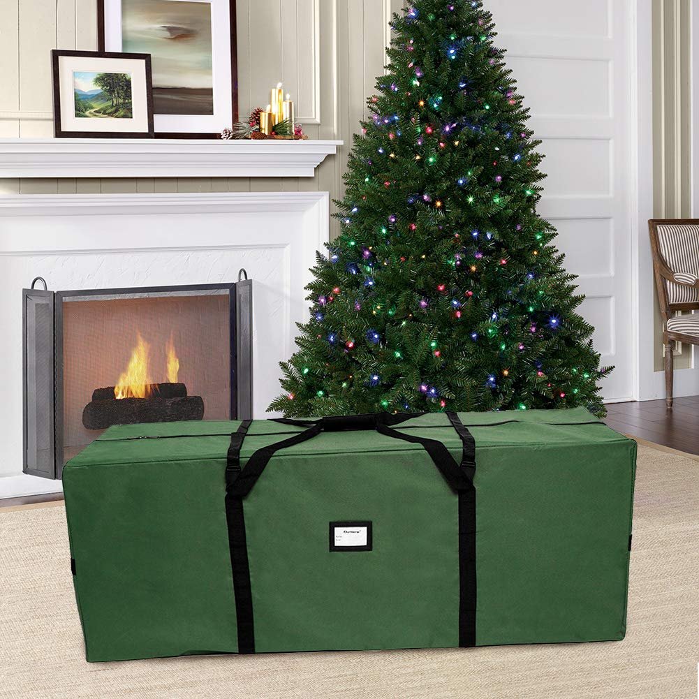 Extra large green Christmas tree storage bag in a festive living room setting with a lit tree and fireplace.