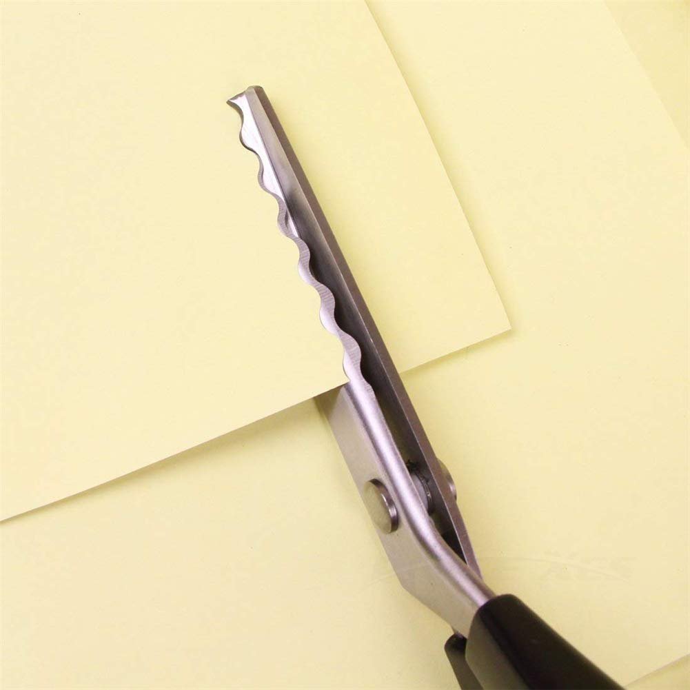 Close-up of pinking shears cutting a piece of light yellow paper, showing the scalloped blade and part of the handle.