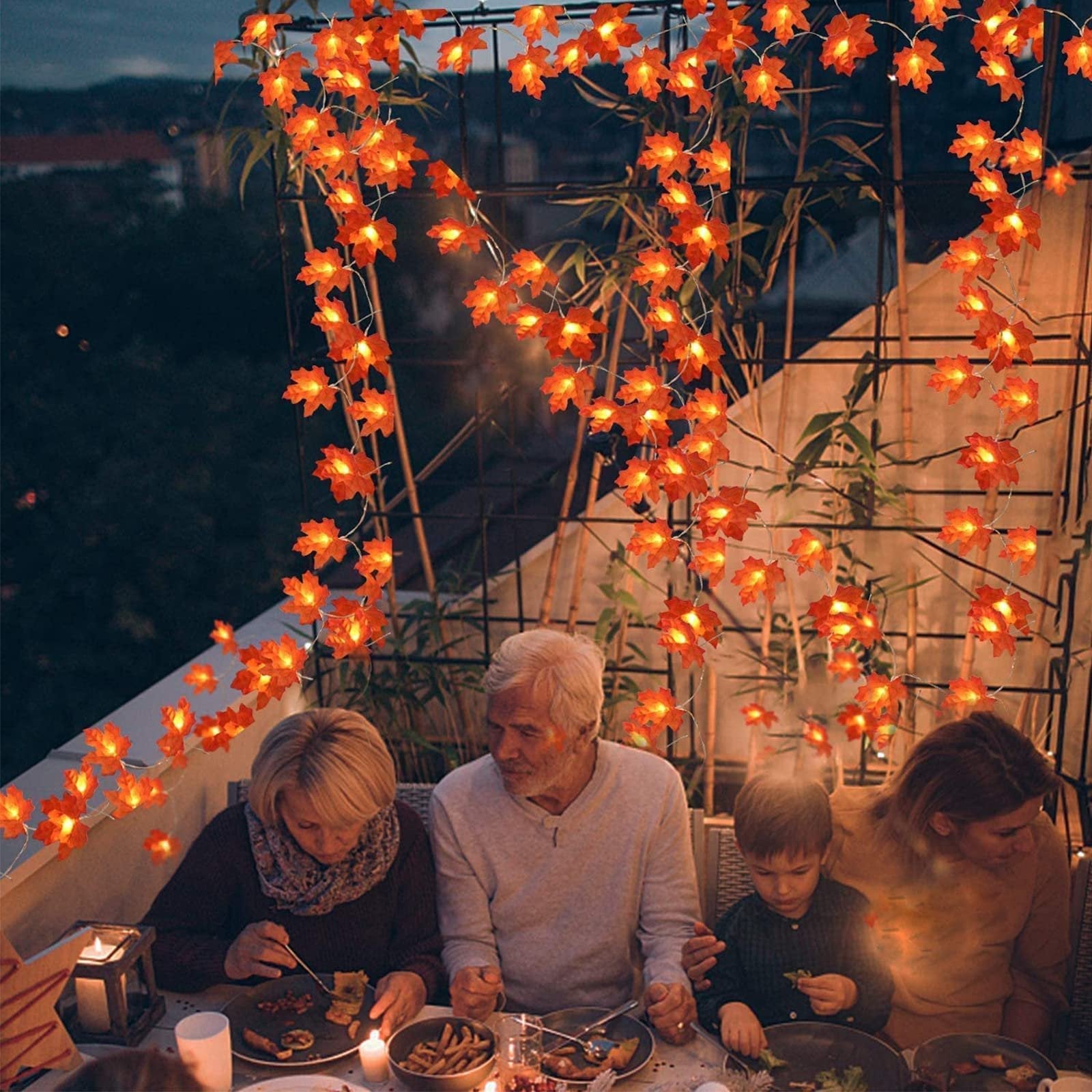 Family enjoying dinner on a balcony decorated with illuminated maple leaf string lights