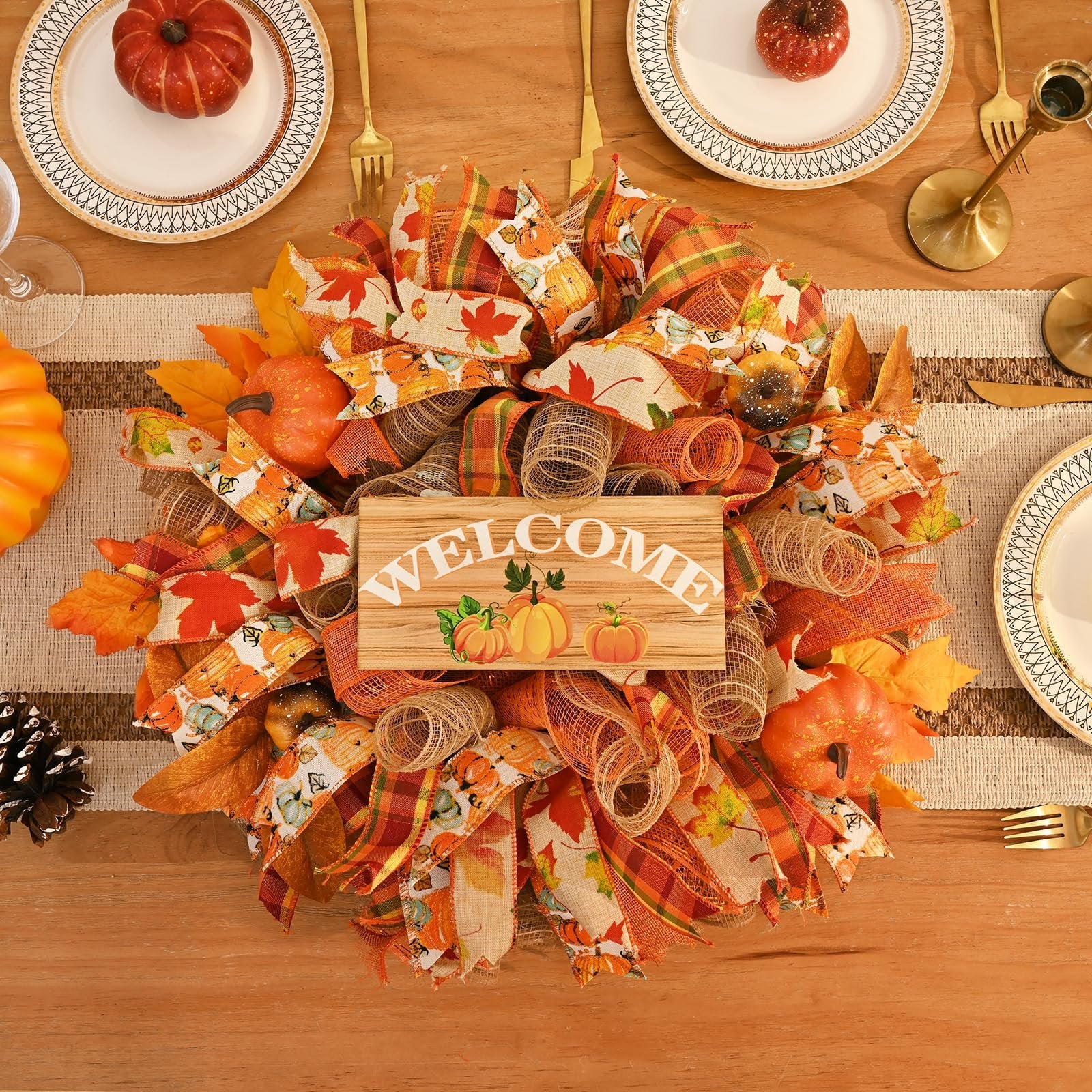 Fall mesh wreath with a wooden welcome sign featuring pumpkins, set on a wooden table with place settings.